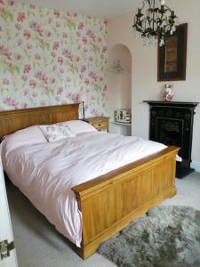 北安普敦Ambles的一间卧室配有一张带粉红色花卉壁纸的木床