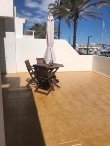 拉萨维纳Apartamentos Mar i Vent Puerto de La Savina Formentera的天井配有桌子和遮阳伞,种有棕榈树