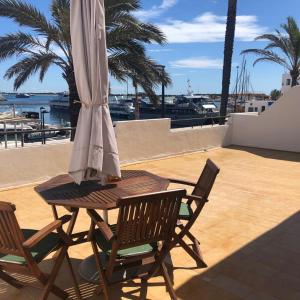 拉萨维纳Apartamentos Mar i Vent Puerto de La Savina Formentera的庭院内桌椅和遮阳伞