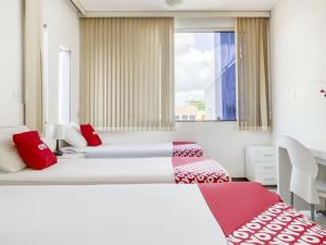 萨尔瓦多OYO Hotel Stella Maris - Salvador的配有红色和白色枕头的客房内的两张床