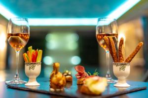 普里什蒂纳普里什蒂纳瑞士钻石酒店的一张桌子,上面放着三杯葡萄酒和一些食物