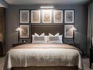 利兹利兹达科他酒店的卧室配有一张大床,墙上挂有四张照片