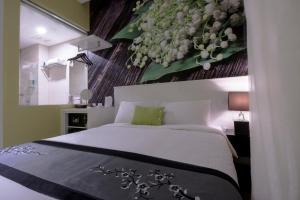 新加坡J8 Hotel的卧室配有一张挂有花卉画的床铺。