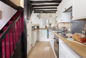 奇平诺顿Church Cottage的一间大厨房,厨房配有白色橱柜和柜台上的红色条纹