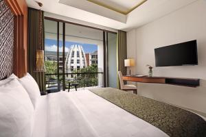 库塔巴厘岛金色郁金香继能度假酒店的酒店客房设有一张床、一张书桌和一个阳台。