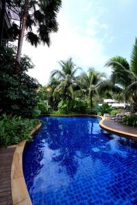 卡塔海滩Kata gardens 2 bedroom near Kata beach 3B的一座种植了棕榈树的蓝色游泳池