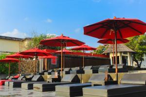 查汶Kirikayan Boutique Resort - SHA Extra Plus的庭院里摆放着一组带红伞的椅子