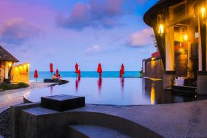查汶Kirikayan Boutique Resort - SHA Extra Plus的一群身着红色长袍的人站在海洋前