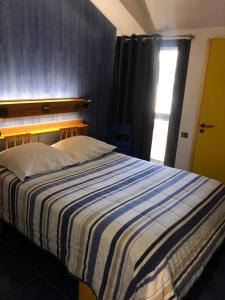 Étagnac埃塔尼亚克酒店的一间卧室配有一张带条纹毯子的床和窗户