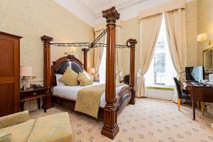 都柏林城堡酒店的一间卧室配有一张床、一张书桌和一台电视