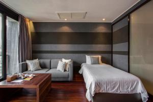 曼谷LUXX Langsuan Hotel - SHA Plus的一间卧室配有一张床和一张沙发