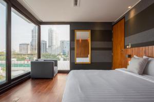 曼谷LUXX Langsuan Hotel - SHA Plus的一间卧室设有一张大床和一个大窗户