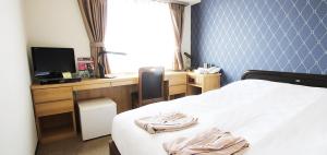 高松Takamatsu City Hotel的一间卧室配有一张床和一张书桌及电视