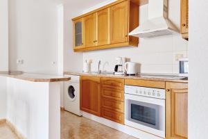 奥里韦拉Playamarina II Rooftop Apartment的厨房配有木制橱柜、洗衣机和烘干机