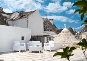 阿尔贝罗贝洛Trulli e Puglia Luxury Suite的一个带白色椅子的庭院和一座建筑