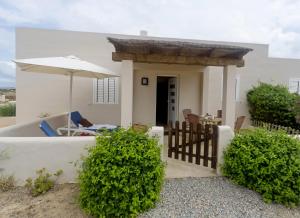 圣费兰-德瑟斯罗Es Garrovers - Formentera Break的一座带雨伞和灌木的小白色房子