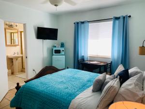 迈阿密海滩Blue House Miami的一间卧室配有一张带蓝色窗帘的床和一扇窗户