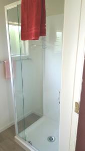 莫拉基Jacks place的浴室里设有玻璃淋浴间,备有红色毛巾