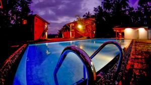 本托塔Amri River Cottages And Ayurvedee Retreat的夜间游泳池,灯光照亮