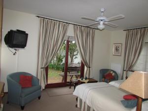 Outeniqua Strand梅尔库特洛夫旅馆的一间卧室配有一张床、两把椅子和电视