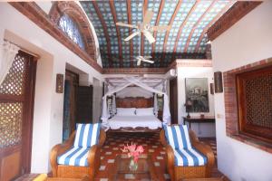 苏弗里耶尔Caille Blanc Villa & Hotel的一间卧室配有一张带两把椅子的床和天花板
