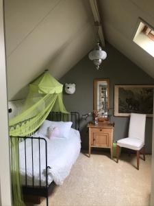 埃曼B&B De Koraal的一间卧室配有一张带绿篷的床