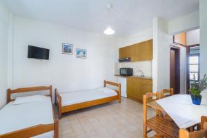 皮加迪卡Kritikos Apartments的带两张床和一张桌子的房间以及一间厨房