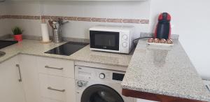 科尼尔-德拉弗龙特拉Apartamento Conil Playa & Centro, perfecto descanso, con Aire Acond y WIFI的厨房配有微波炉和洗衣机。