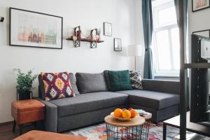维也纳Design Apartment with King Size Bed - Six Minutes to Opera的客厅配有灰色的沙发和桌子上的橙子