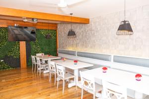 西湾La Placita Inn的餐厅设有白色的桌椅和平面电视。