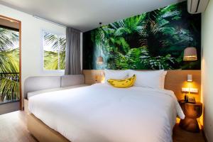 查汶The Stay Chaweng Beach Resort- SHA Plus的卧室配有一张大床,墙上挂着香蕉