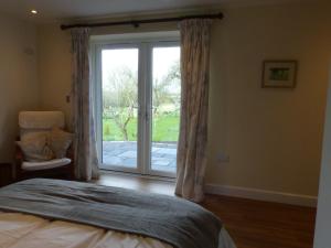 格拉斯顿伯里The Woodshed - A newly built, 2 bedroom, cottage near Glastonbury的一间卧室设有一张床和一个滑动玻璃门