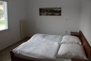 内亚卡瓦里Pares Comfort Apartment的卧室里的一张未铺好的床,墙上挂着一幅画