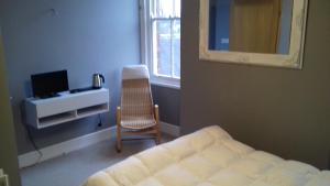马基特德雷顿Lansdown House Bed & Breakfast的一间卧室配有一张床、一把椅子和镜子