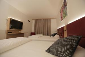 默费尔登-瓦尔多夫Galeria Airport Hotel的酒店客房设有两张床和一台平面电视。