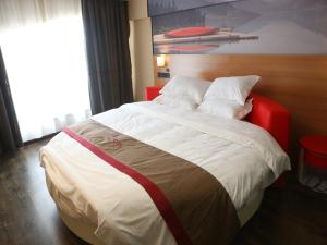 盐城尚客优酒店江苏盐城阜宁县金沙湖店的一间卧室配有一张大床和红色床头板