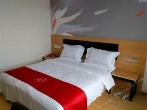 南昌尚客优酒店江西南昌中山路八一馆地铁站店的一间卧室配有一张带红白毯子的床