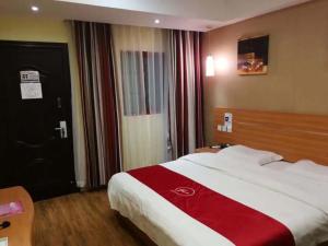 安顺尚客优酒店贵州安顺黄果树风景名胜区店的一间卧室配有一张大床,铺有红白毯子