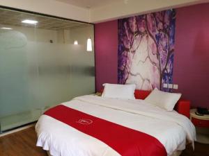 安顺尚客优酒店贵州安顺黄果树风景名胜区店的一间卧室配有一张大床,铺有红白毯子