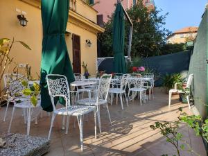 圣玛格丽塔-利古雷Sabini Rentals - Affittacamere的庭院配有白色的桌椅和绿色的遮阳伞。