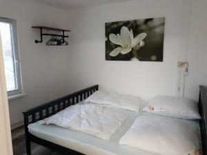 FlessenowFerienwohnung Lindenstraße 8L的一张带白色枕头的床和一张花的照片