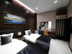 塔什干Home Boutique Hotel的酒店客房配有两张床和一张书桌