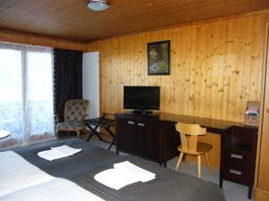 KrattigenBellevue Bären Hotel & Restaurant的一间卧室配有一张床和一张书桌及电视