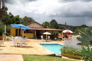 巴埃彭迪Pousada Cachoeirinha的一座房子,设有一座带椅子和遮阳伞的游泳池