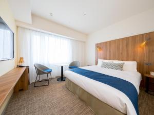 那霸Tokyu Stay Okinawa Naha的酒店客房设有一张大床和一张书桌。