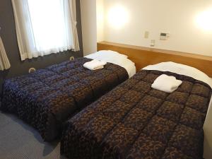 东京新宿威尔酒店的两张位于酒店客房的床,配有毛巾