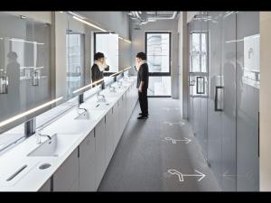 名古屋9h nine hours Nagoya station的站在带水槽和镜子的浴室中的男人