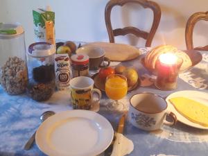 布鲁塞尔Chez Mimi - chambre vue parc的桌子上放有杯子和盘子,食物和水果