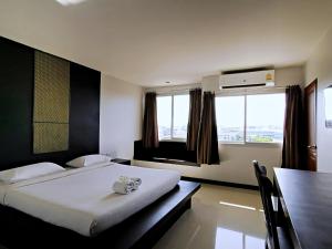春蓬娜娜武里酒店的卧室配有床、桌子和窗户。
