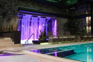 尤尔马拉波罗的海海滩酒店及SPA的一个带椅子和紫色照明的游泳池